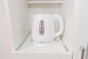 a white appliance sitting on a shelf in a kitchen at 春明House in Tokyo