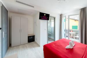 a white bunny sitting on a red bed in a bedroom at Hotel Romantik & Depandance in Lignano Sabbiadoro