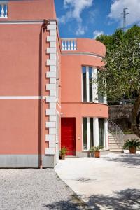 un edificio de ladrillo rojo con puerta roja en Alma Turismo Apartment, en SantʼAngelo di Brolo