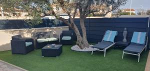 a group of chairs and a tree in a yard at le jardin de Marie in Le Grau-du-Roi