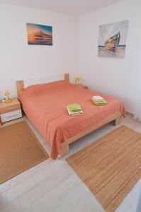 a bedroom with a bed with orange sheets and two rugs at Apartmani Mentha & Lipa in Novi Vinodolski