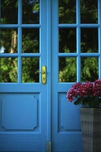 Una puerta azul con un jarrón de flores en una cesta en Hotel Sundblick en Altefähr