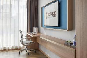 a room with a desk with a chair and a tv at 夏朗酒店 Xialang Hotel in Guangzhou