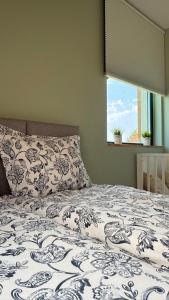 a bed with a blue and white comforter and a window at Liwia Park Green House in Niechorze