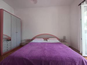 a bedroom with a purple bed and a large mirror at Apartment house Nena in Krk