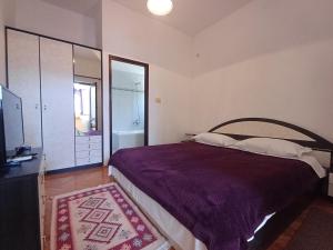 a bedroom with a large bed with a purple blanket at Apartment house Nena in Krk
