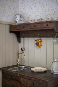 a kitchen counter with a sink and a shelf with dishes at Majatalo Kukkasrinne in Lahti