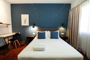 a bedroom with a large bed with blue walls and a desk at Bukit Damansara Terrace in Kuala Lumpur