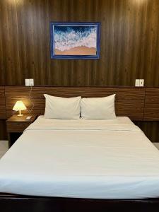 a bedroom with a large white bed with wooden walls at BeSea Hotel in Danang
