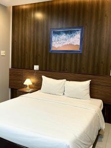 a bedroom with a large white bed with a wooden wall at BeSea Hotel in Danang