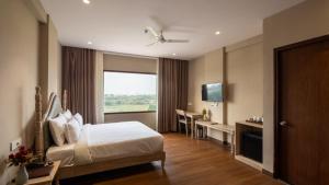 a bedroom with a bed and a desk and a television at Pallacia A Luxury Hotel in Beāwar