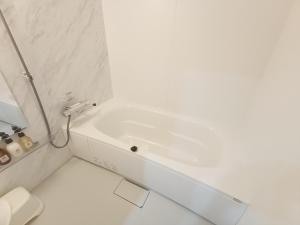 a white bathroom with a tub and a toilet at Kariyushi Condominium Resort Sea Side House in Nago