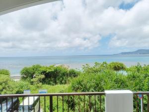 a view of the beach from the balcony of a condo at Kariyushi Condominium Resort Sea Side House in Nago