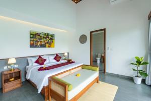 a bedroom with a large bed with a bench in it at Alam Dana Ubud in Ubud