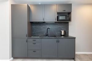 a kitchen with white cabinets and a sink and a microwave at Trumpalaikė butų nuoma Kaune prie Klinikų SELF CHECK-IN in Kaunas