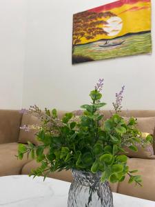 a vase with a plant in front of a couch at Himawari House Pekanbaru in Palas 2 +29 photos