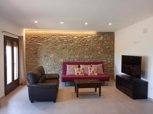 a living room with a red couch and a tv at L'horitzó II in Llado