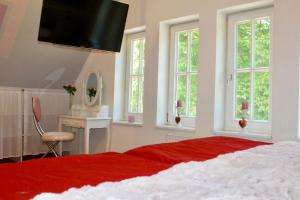 1 dormitorio con 1 cama con manta roja y ventanas en Stilvolles Landhaus mit Flair, en Menslage