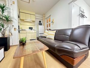ein Ledersofa im Wohnzimmer mit einem Tisch in der Unterkunft NewOpenSapporo TanukikojiShimaya Building403 in Sapporo + 37 Fotos