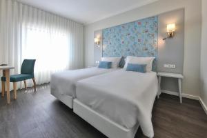 a bedroom with a large white bed and a desk at Agua Hotels Alvor Jardim in Alvor
