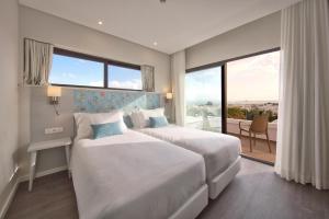 a hotel room with two beds and a large window at Agua Hotels Alvor Jardim in Alvor