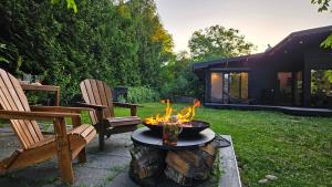 a fire pit in a yard with two chairs at Black Walnut House with indoor outdoor fireplace in Izvoarele