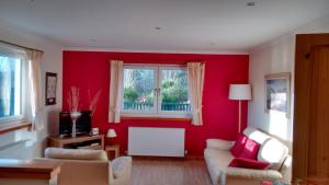 a living room with red walls and a window at Ornum Cottage in Beauly