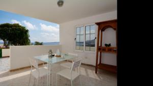 ein Esszimmer mit einem Glastisch und weißen Stühlen in der Unterkunft Apartment Erizo with Sea Views Punta Mujeres By PVL in Punta de Mujeres
