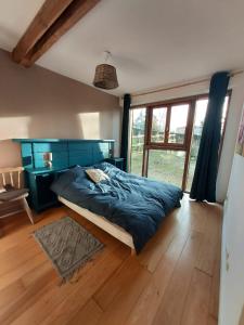 a bedroom with a bed and a large window at La caronnière in Mervent