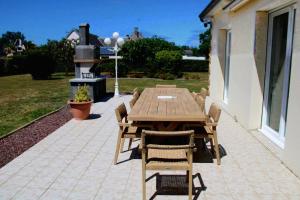 a wooden table and chairs on a patio at Villa DES COEURS NORMANDS in Pirou