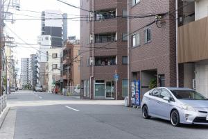 Un coche blanco estacionado al costado de una calle de la ciudad. en b&難波3号店, en Osaka