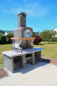 a stone bench with a stove in a park at Villa DES COEURS NORMANDS in Pirou