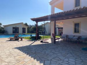 a patio in front of a house with a pool at West Pool House in Kineta