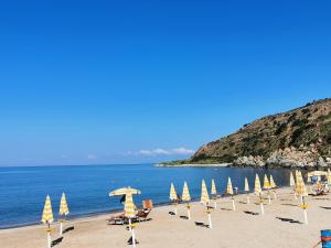 a group of umbrellas and chairs on a beach at Casa Kalavrìa a 50mt dal mare in Nicotera Marina