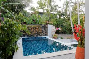 a swimming pool in a garden with plants at Jampun Pool Villa in Klong Muang Beach