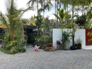 a child sitting on the gravel in a garden at Jampun Pool Villa in Klong Muang Beach