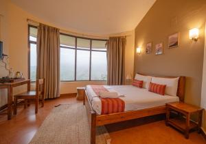 una camera da letto con un letto, una scrivania e una finestra di Aruvi Mountain Villa Vagamon by VOYE HOMES a Vagamon Altre 48 foto