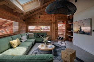 a living room with a green couch and a table at Chalet Plume - OVO Network in Morzine