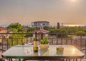 爱琴娜岛Ivy's Light的阳台上的一张桌子上摆着一瓶葡萄酒和一些酒杯