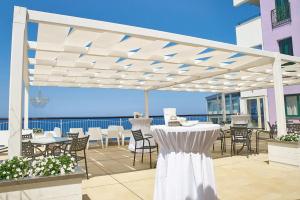a white pergola with tables and chairs on a patio at Capo Skino Park Hotel in Gioiosa Marea