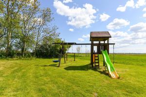 Un parque infantil con dos columpios y una torre. en Ferienwohnung Sternstunde, en Bensersiel