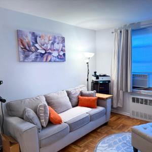 a living room with a gray couch with orange pillows at Welcome to New Rochelle Studio in New Rochelle