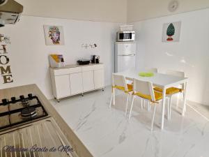 a white kitchen with a white table and chairs at Maison Etoile de Mer in Agnone Bagni