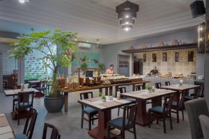 ein Restaurant mit Tischen und Stühlen und ein Koch in der Küche in der Unterkunft Memoire d' Angkor Boutique Hotel in Siem Reap