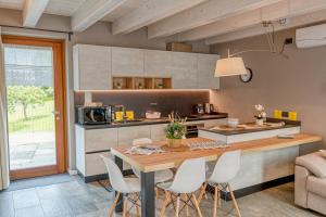 a kitchen with a wooden table and white chairs at La Volta - Historic Molino Maufet Watermill - Lake Como in Colico