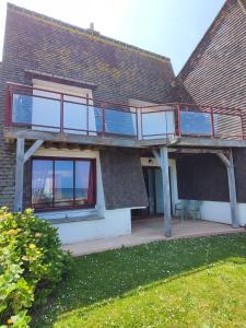 a house with a deck on the side of it at Face a la mer in Courseulles-sur-Mer