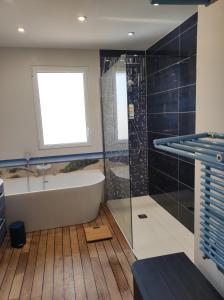 a bathroom with a tub and a shower and a window at Face a la mer in Courseulles-sur-Mer