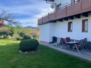eine Terrasse mit Tisch und Stühlen neben einem Gebäude in der Unterkunft Ferienwohnung Eifler in Lam