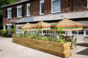 ein Restaurant mit Tischen und Sonnenschirmen vor einem Gebäude in der Unterkunft The Ragged Robin - A Heartwood Inn in Godalming