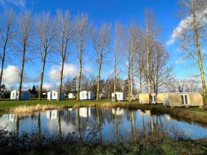 a group of tents and trees next to a pond at Camping Le Romantic in Steenvoorde